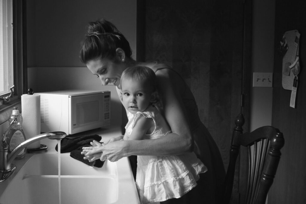 mom washing baby daughters hands in sink